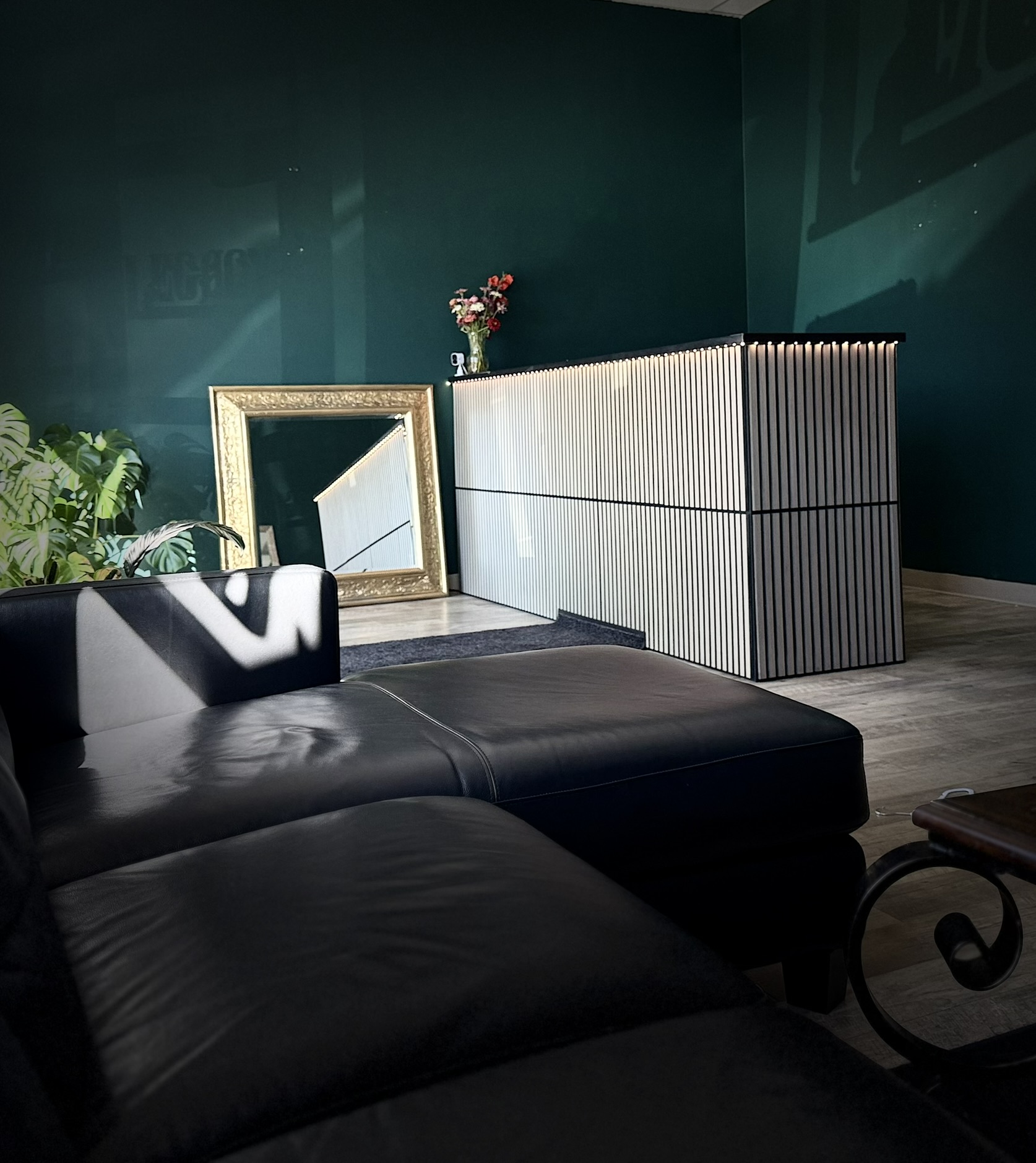 Inside Legacy Tattoo Studio — the waiting area with a leather sectional, reception desk and a gold-framed mirror